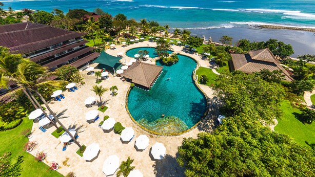 Un resort con una gran piscina, zona de playa y vistas al océano.