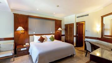 Una habitación de hotel con una cama grande, mesitas de noche, un escritorio y un espejo.