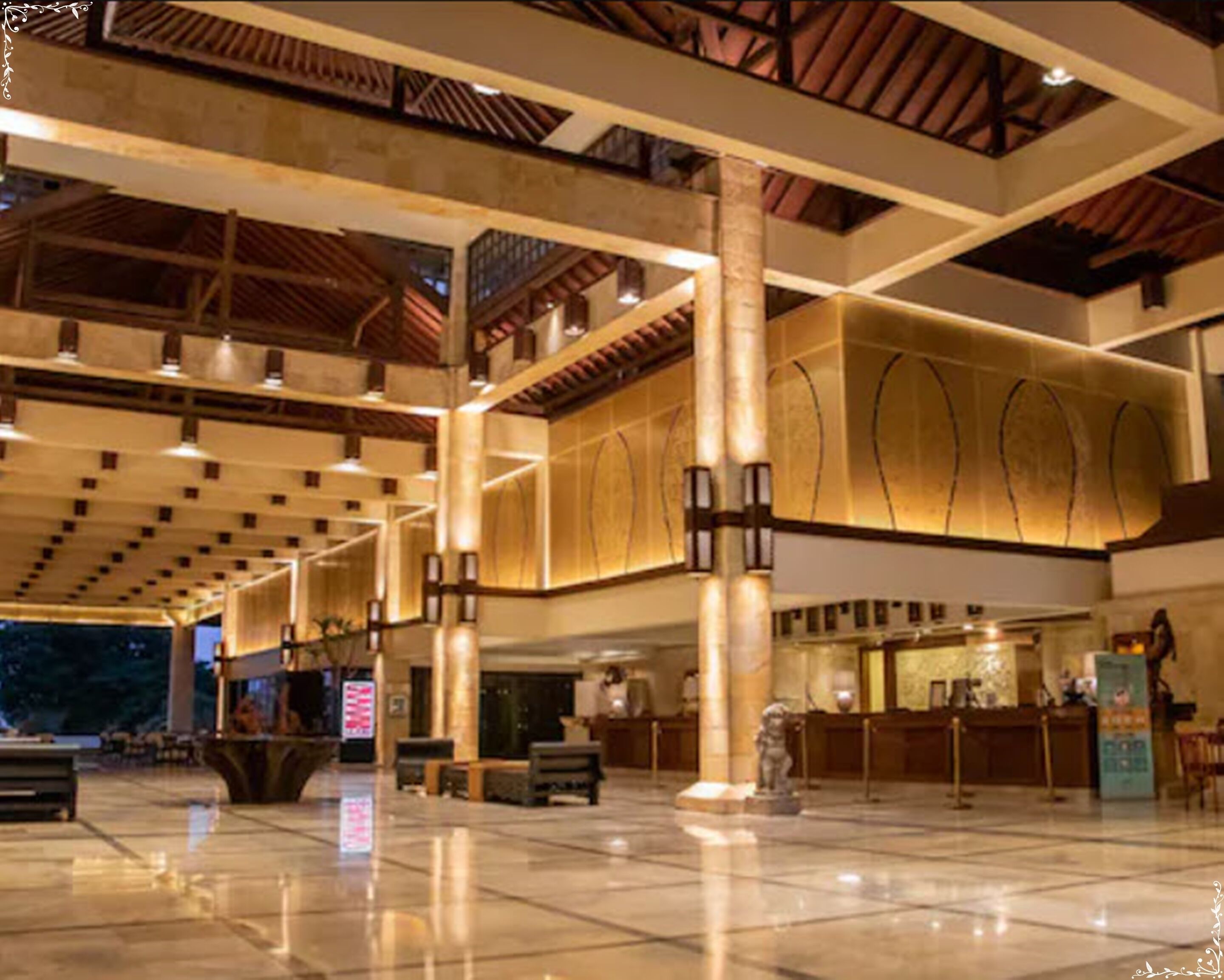Un amplio vestíbulo con techos altos, grandes columnas y una mesa de recepción.