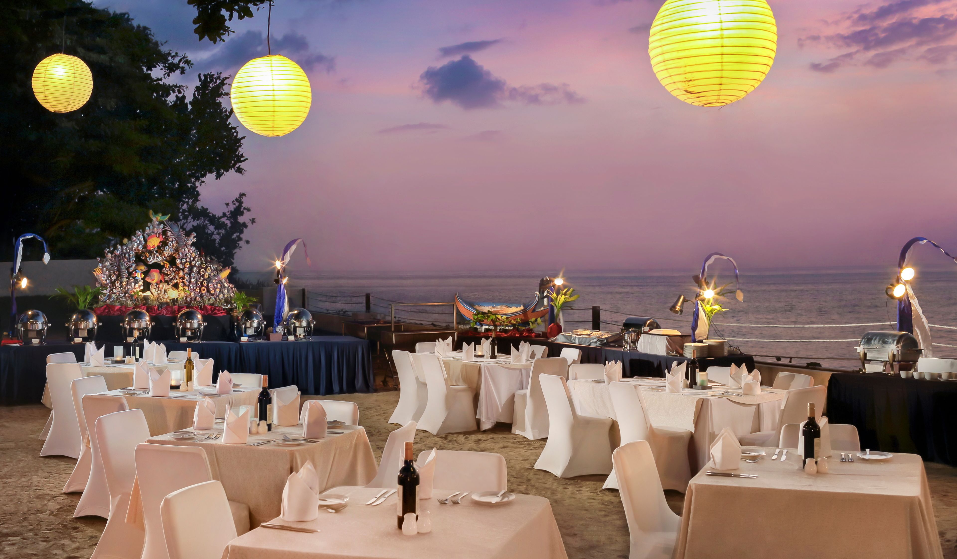 Un área de comedor al aire libre con mesas dispuestas para una comida, con vistas al mar.