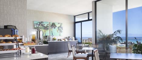 A modern kitchen with a breakfast bar, large windows, and a view of the ocean.