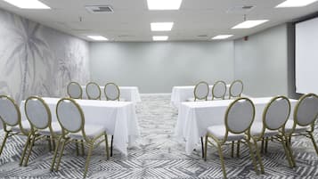 Un salón de conferencias con una mesa larga, sillas y una alfombra estampada.