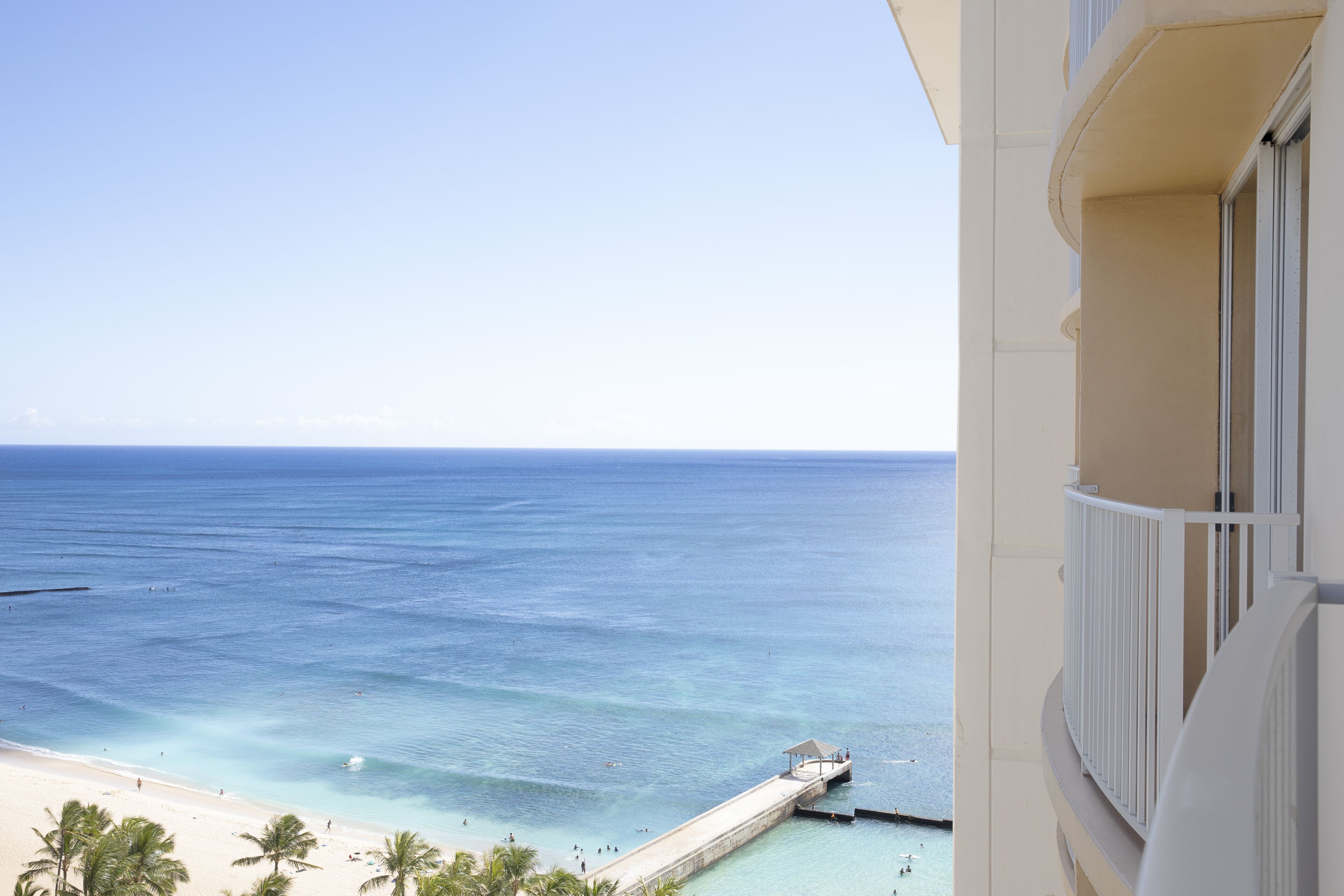 A balcony with a view of a beach and the ocean.