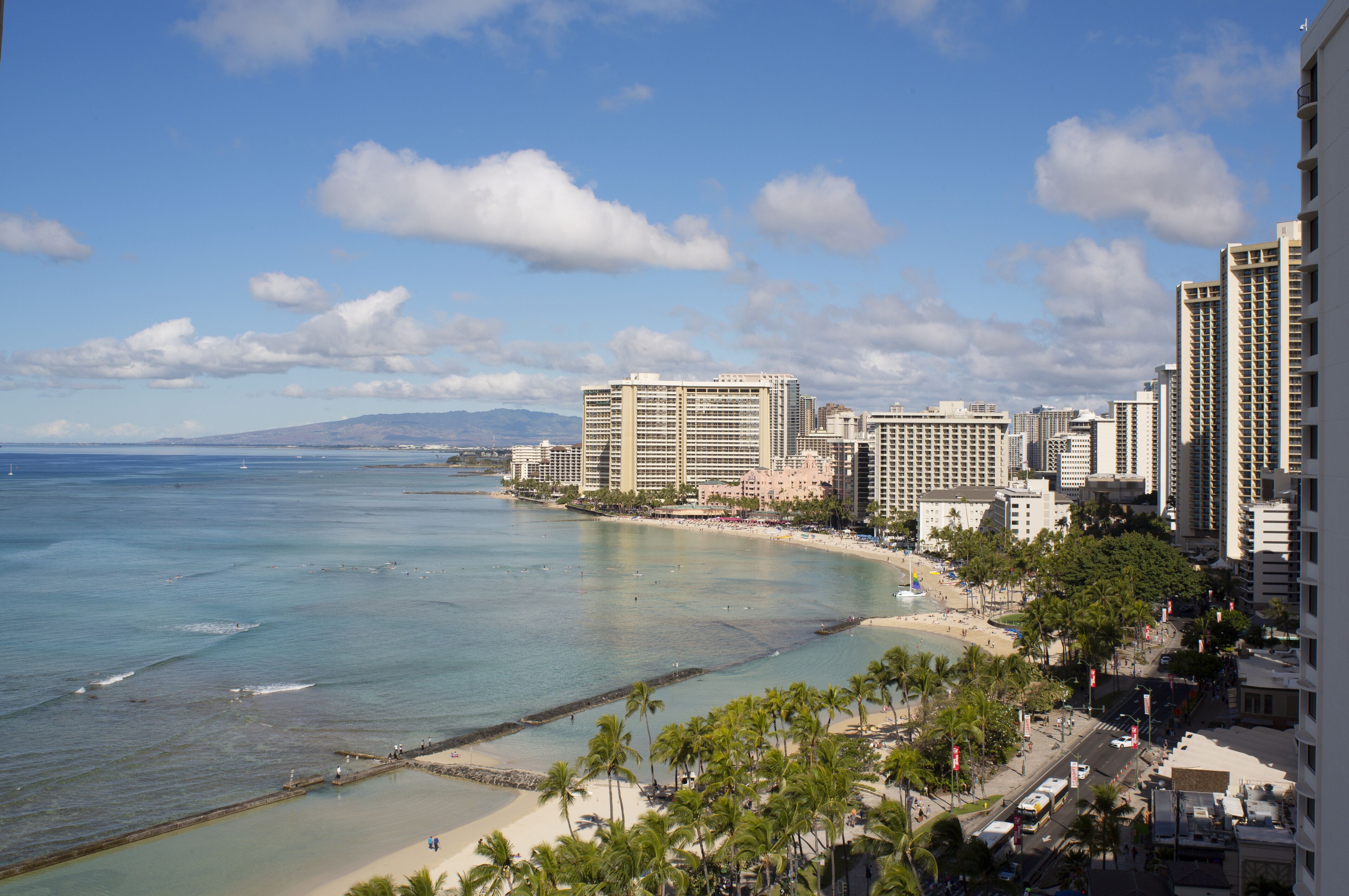 A coastal cityscape with high-rise buildings, a beach, and clear skies.