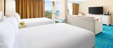 A hotel room with two beds, a TV, a balcony with curtains, and a blue carpet.