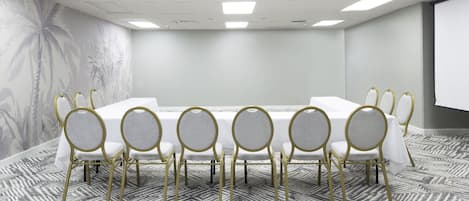 A conference room with a long table, six chairs, and a projector screen.
