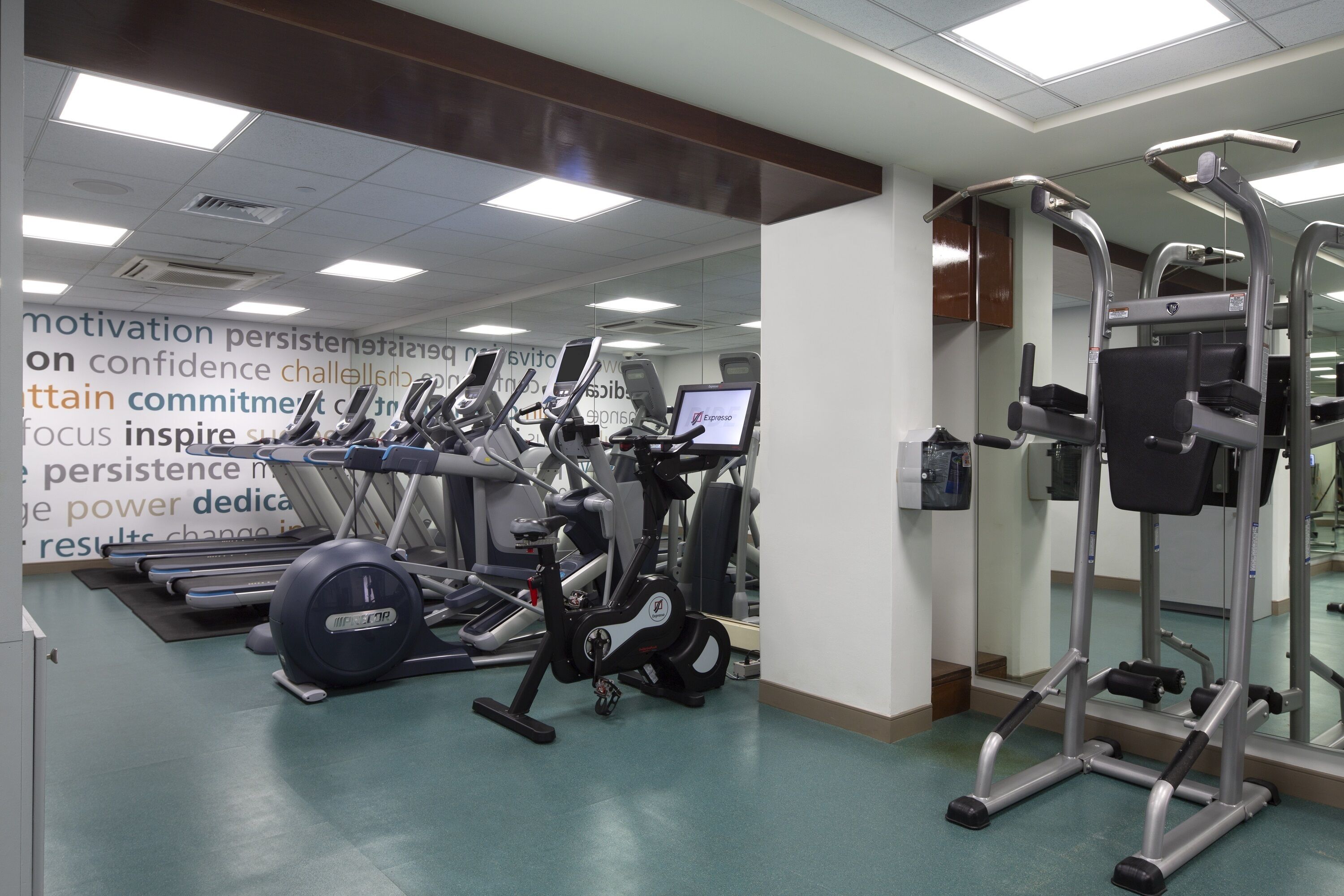 Ein Fitnessstudio mit verschiedenen Trainingsgeräten, darunter Laufbänder und Kraftgeräte.