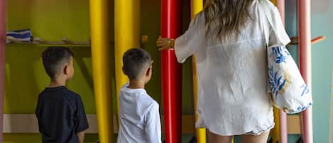 A woman and two children standing in front of a wall with surfboards.