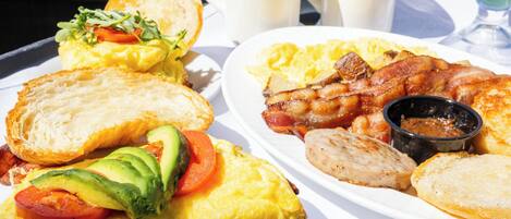 A breakfast tray with toast, eggs, bacon, avocado, and tomato slices.