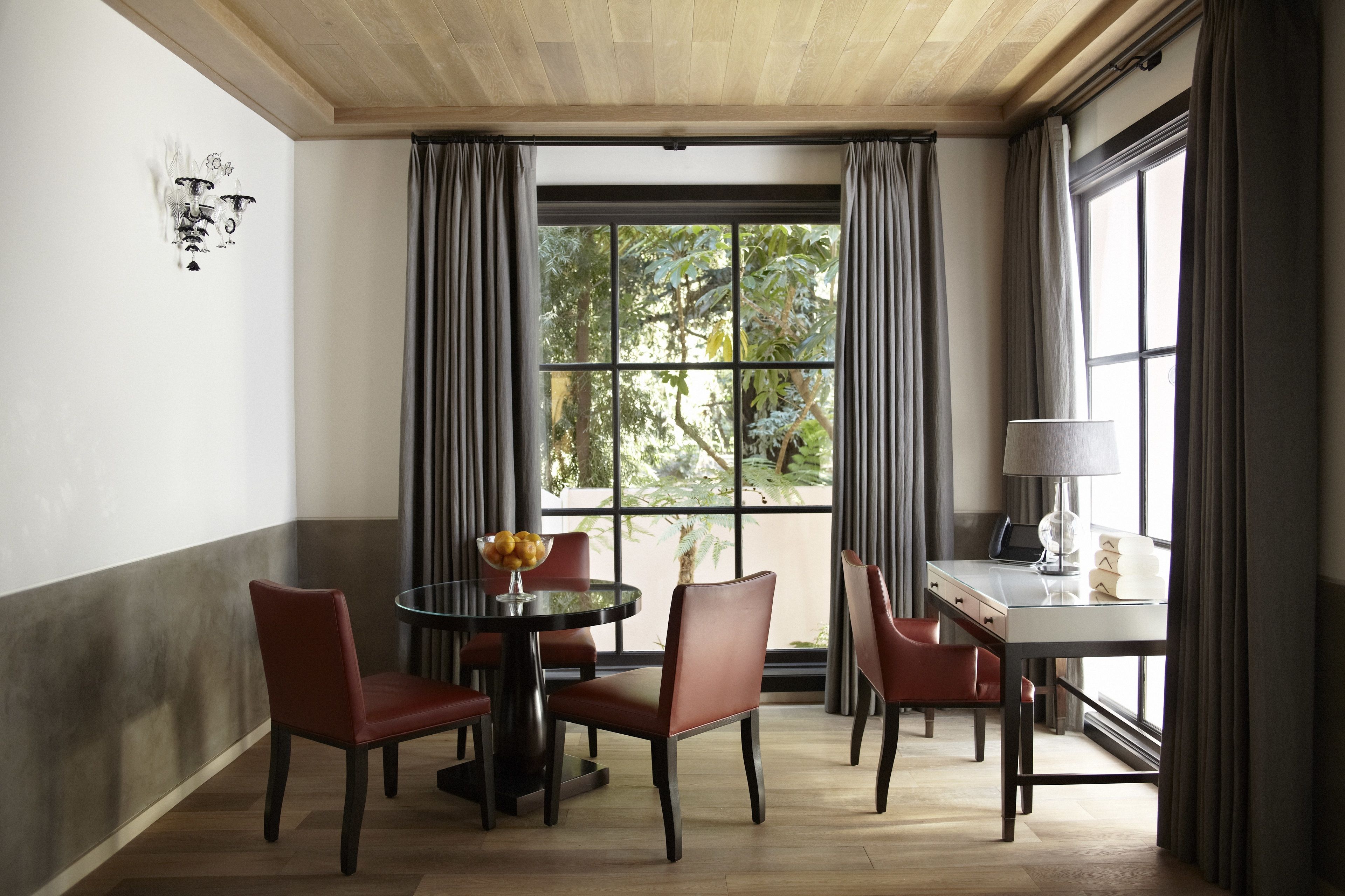 A dining area with a round table, four chairs, a bowl of fruit, and a laptop on a desk.