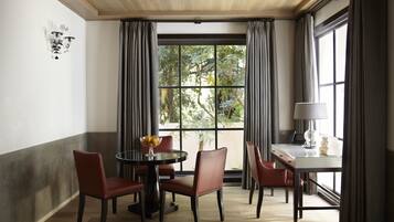 A dining area with a round table, four chairs, a bowl of fruit, and a laptop on a desk.