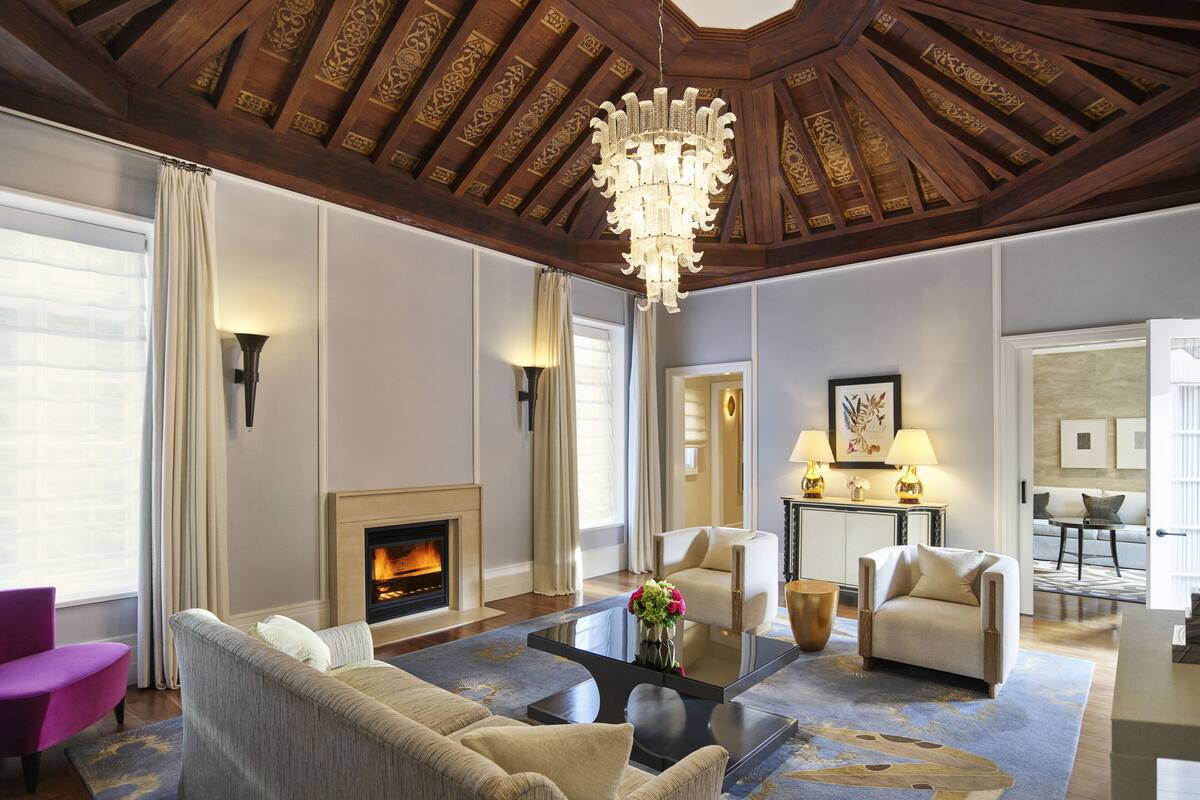 A spacious living room with a fireplace, a chandelier, and a modern sofa.