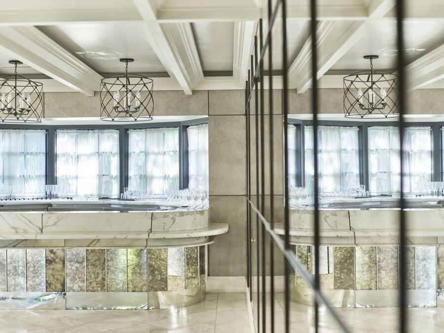 A modern interior with a marble reception desk, large windows with sheer curtains, and geometric pendant lighting.