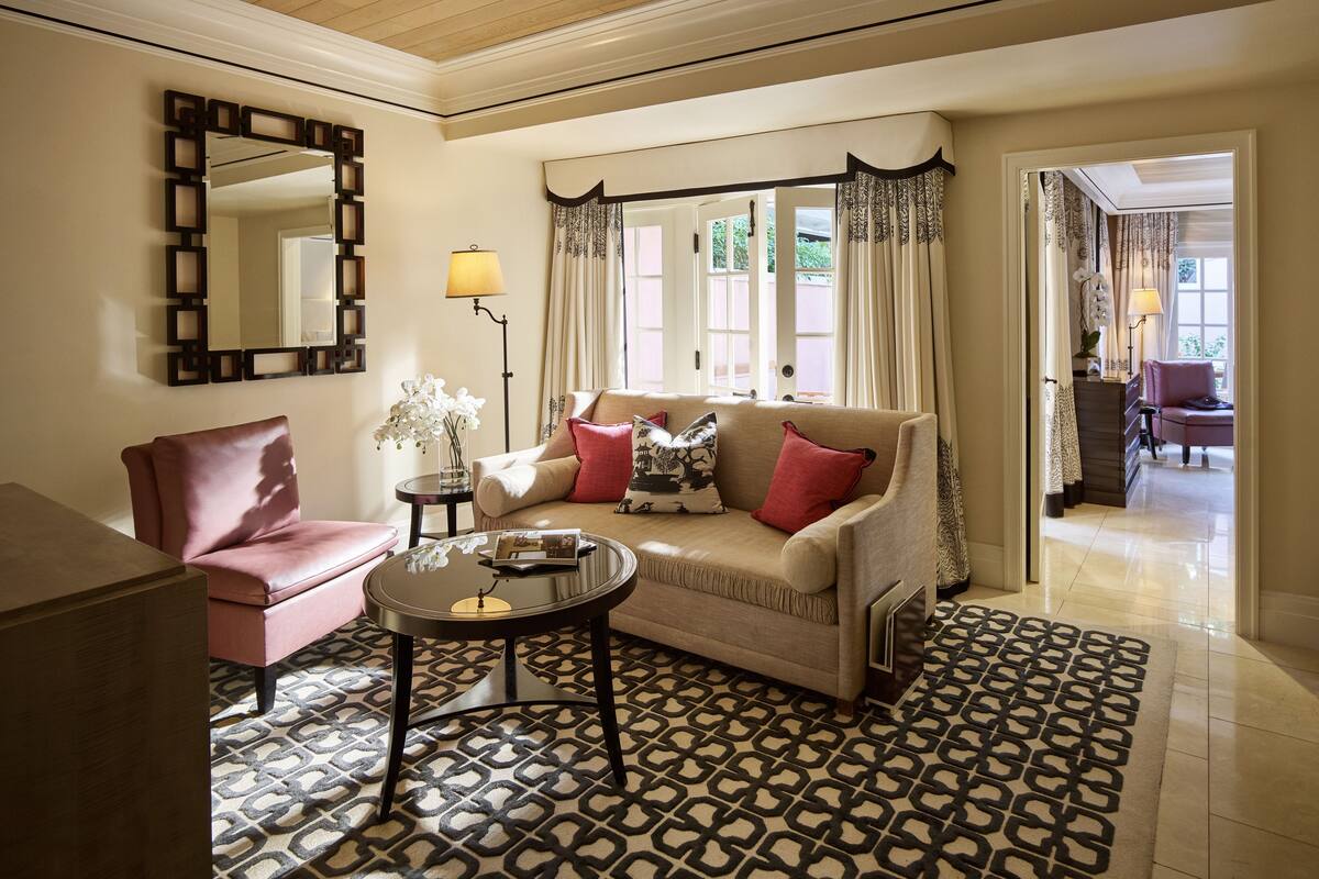 A living room with a beige sofa, a pink armchair, a round coffee table, and a patterned rug.