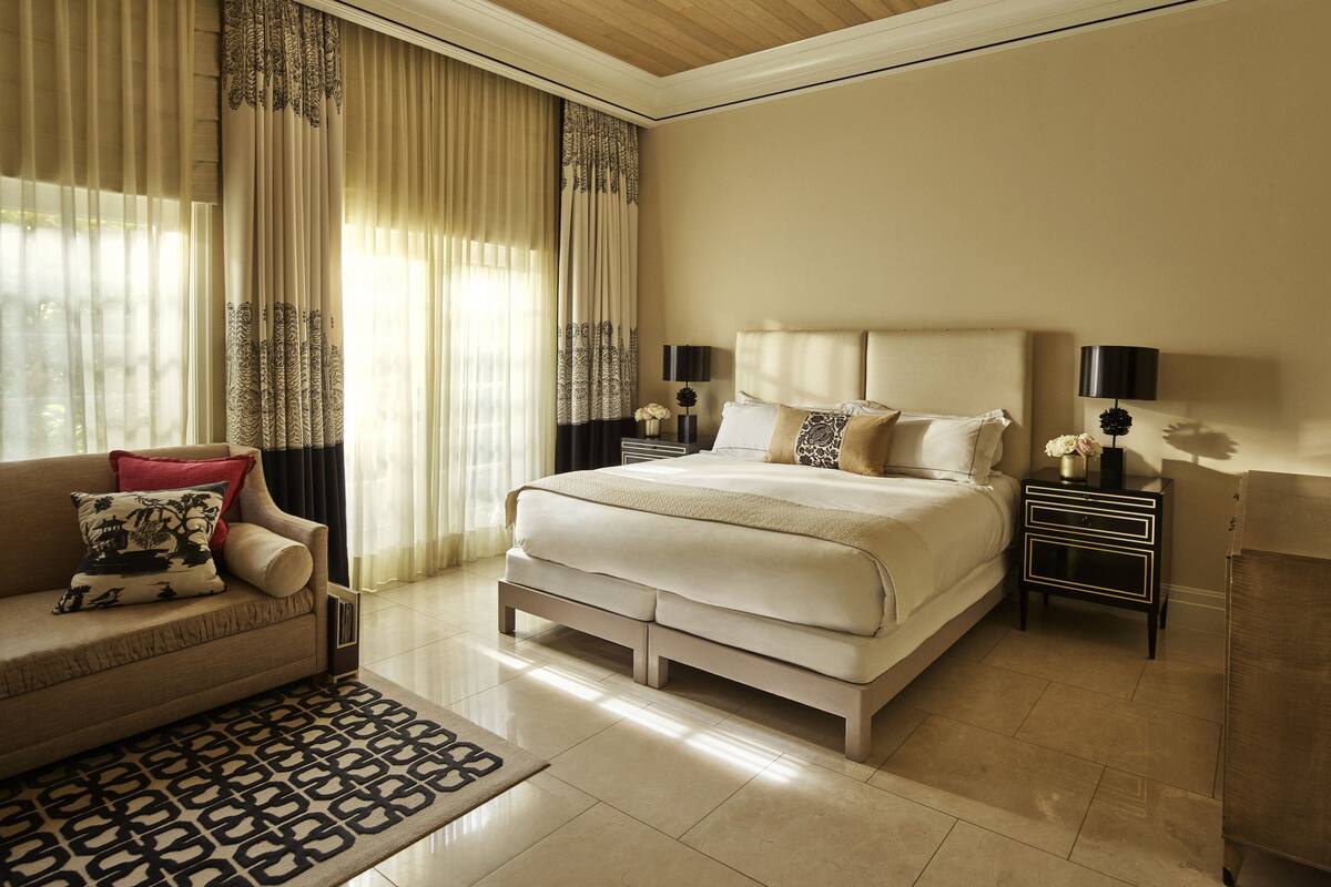 A spacious bedroom with a large bed, a sofa, and a nightstand with lamps.