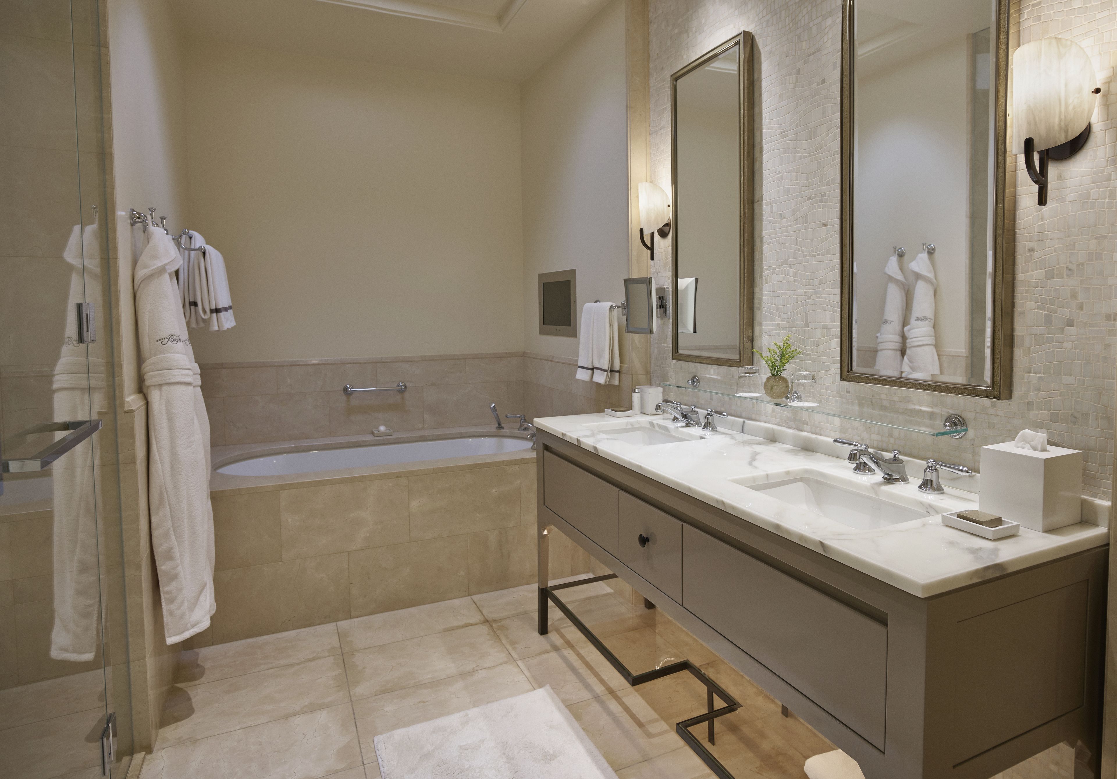 A modern bathroom with a large bathtub, double sinks, and a large mirror.