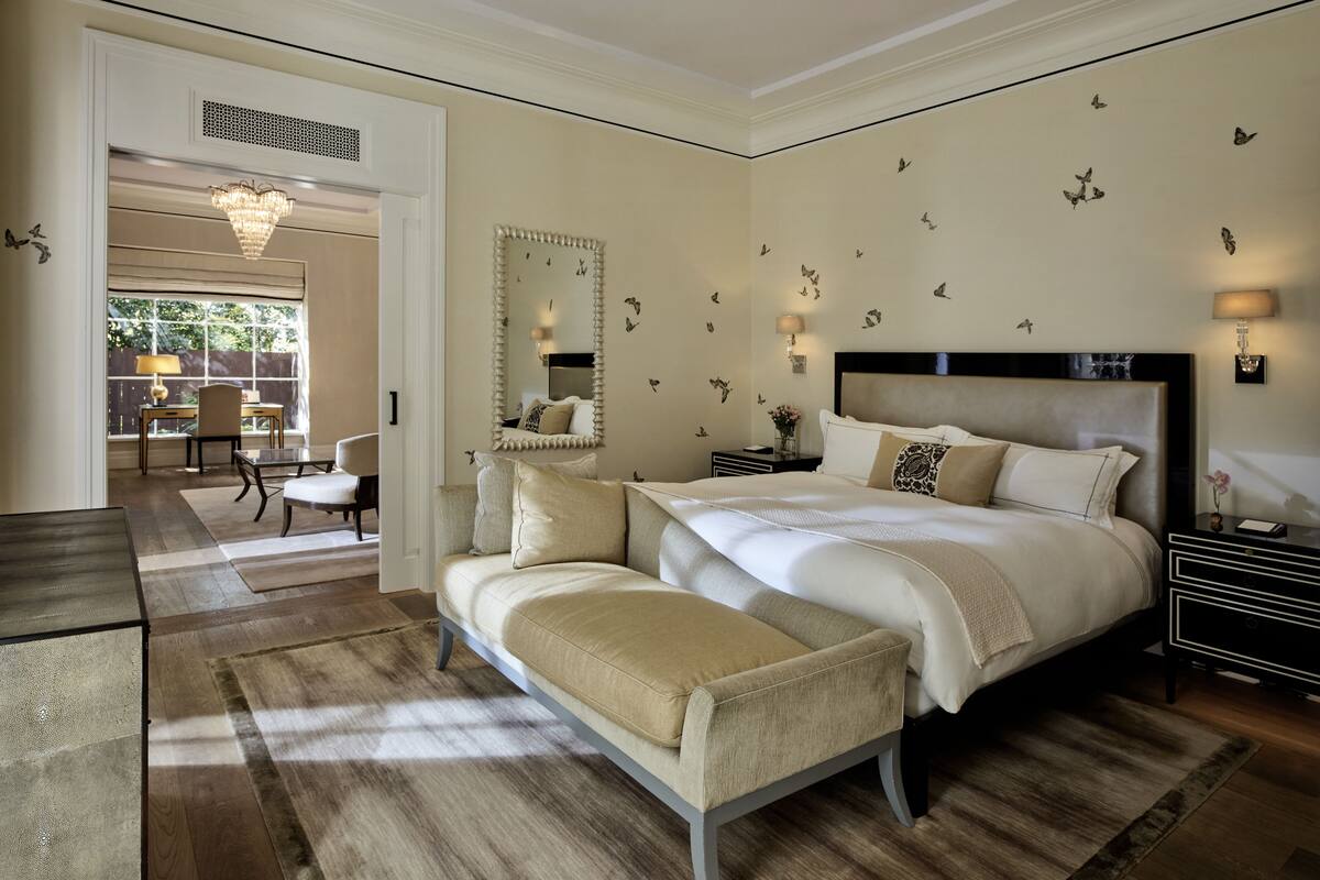 A bedroom with a large bed, a bench, a nightstand, a mirror, and butterfly wall decals.