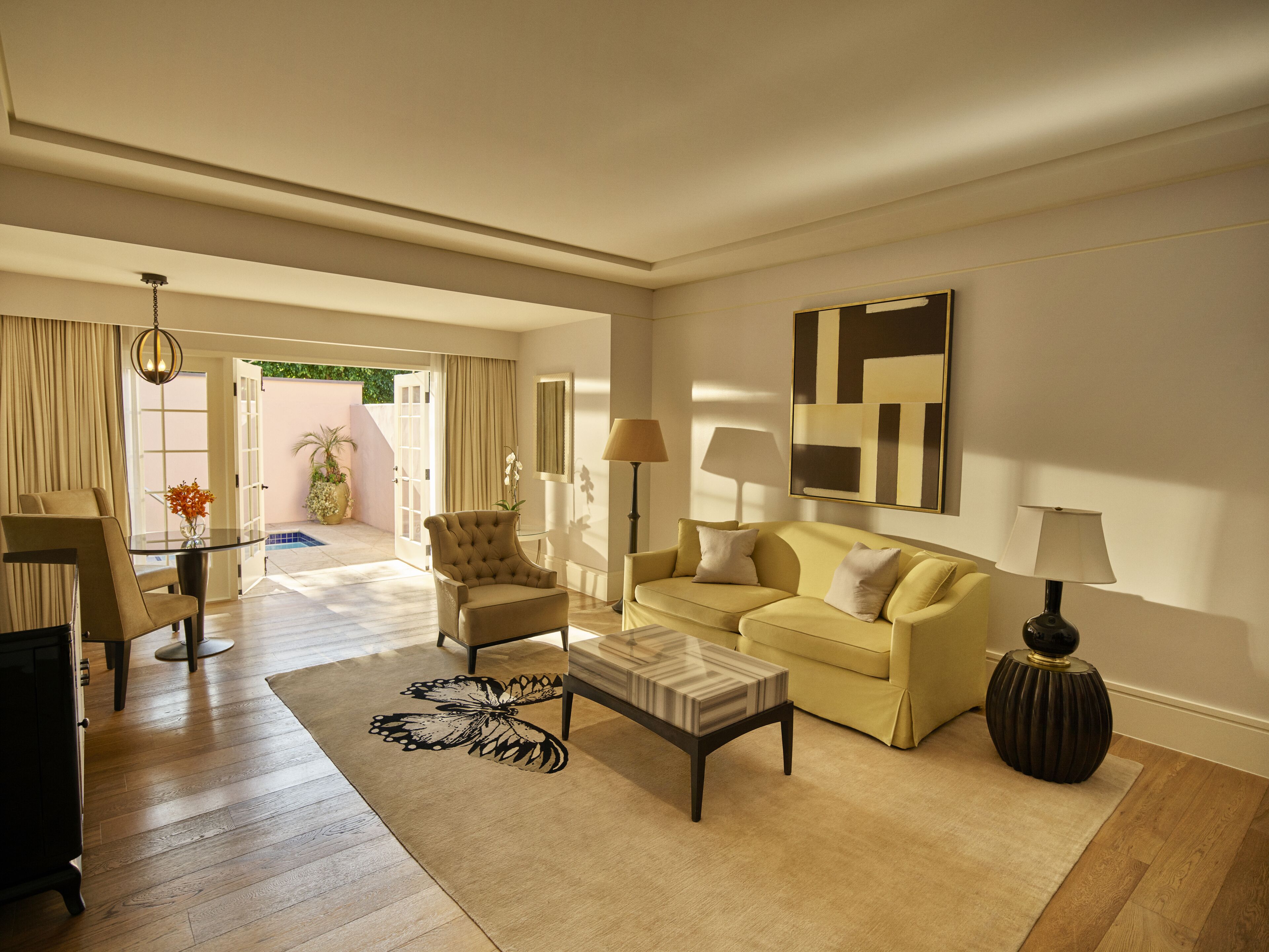 A spacious living room with a sofa, armchair, coffee table, and a rug.