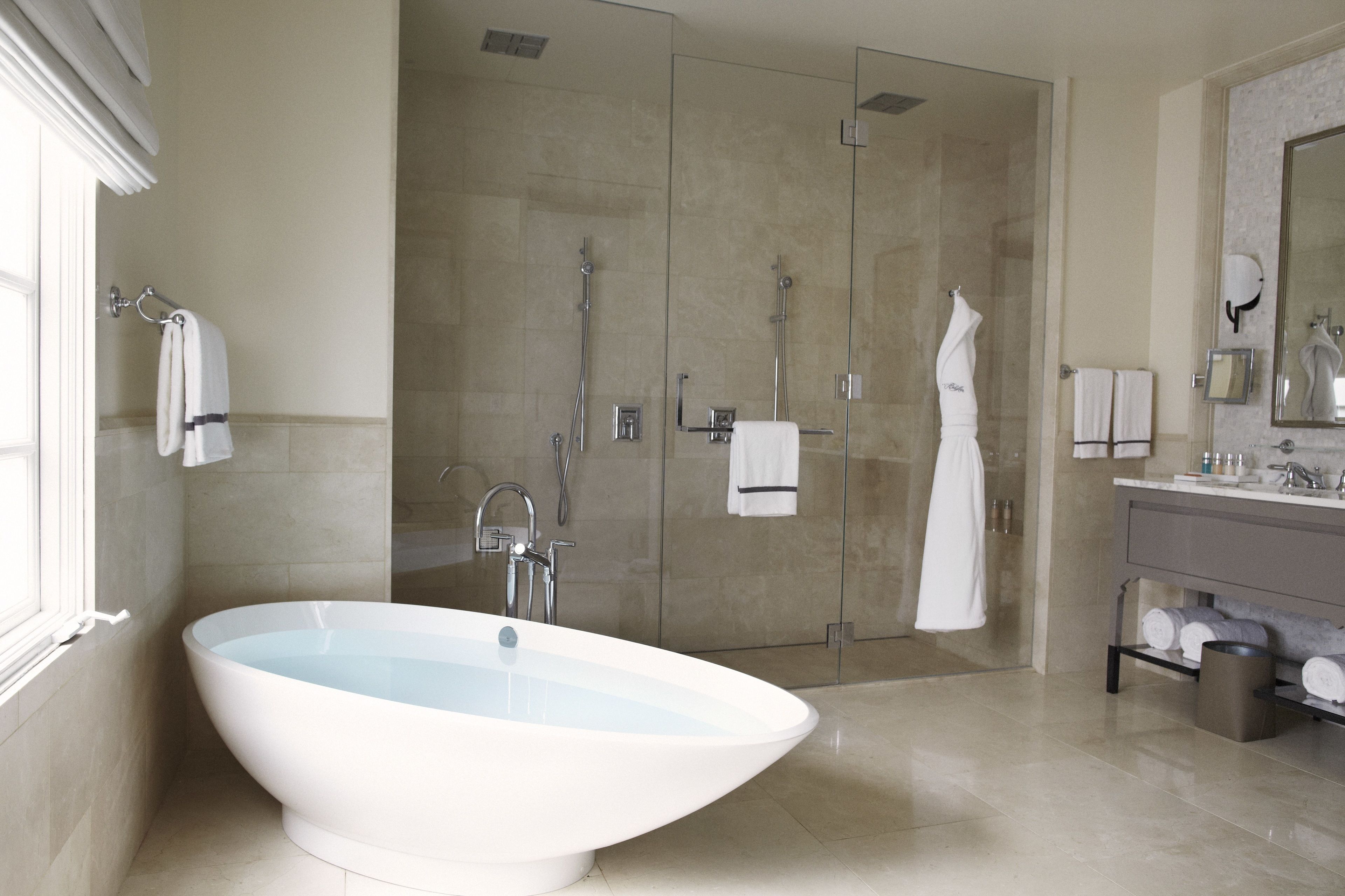 Une salle de bain moderne avec une baignoire sur pieds, une douche à l’italienne et un meuble-lavabo avec un miroir.