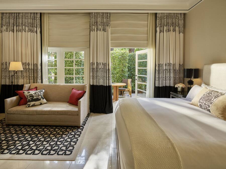 Una camera d'albergo con un letto, un divano, un tavolino e delle tende.