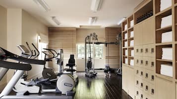Ein Fitnessraum mit Trainingsgeräten, Holfachschränken und einem Fenster, das für natürliches Licht sorgt.