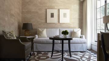 Una sala de estar moderna con una pared beige con textura, un sofá blanco, una mesa de centro negra redonda y una alfombra estampada.