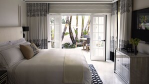 A bedroom with a large bed, a desk, and a view of the outdoors. - Hotel Bel-Air - Dorchester Collection (Los Angeles)