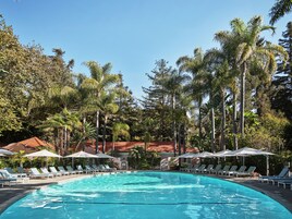 Una piscina al aire libre, sombrillas, sillones reclinables de piscina