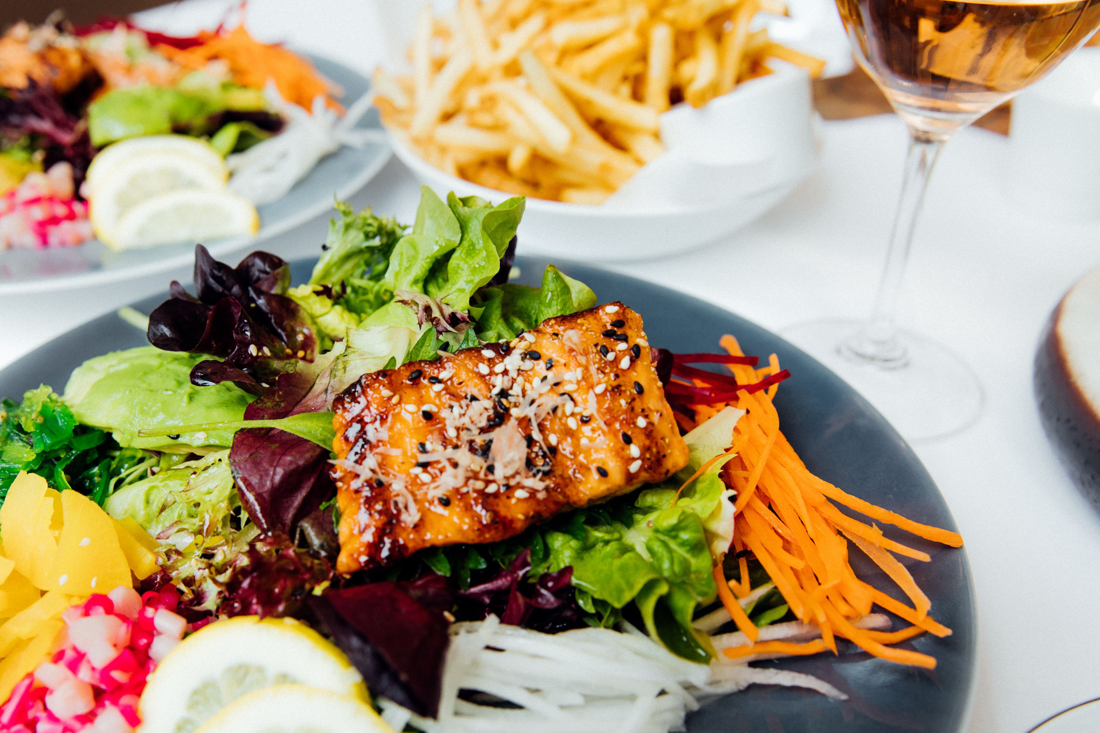 A plate of food with salmon, salad, and fries.