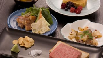 A variety of dishes on a table, including sushi, sashimi, and a dessert with berries.