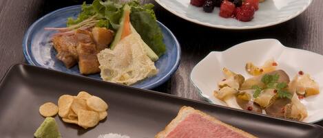 Variedad de platos en una mesa, incluyendo sushi, sashimi y un postre con frutos rojos.