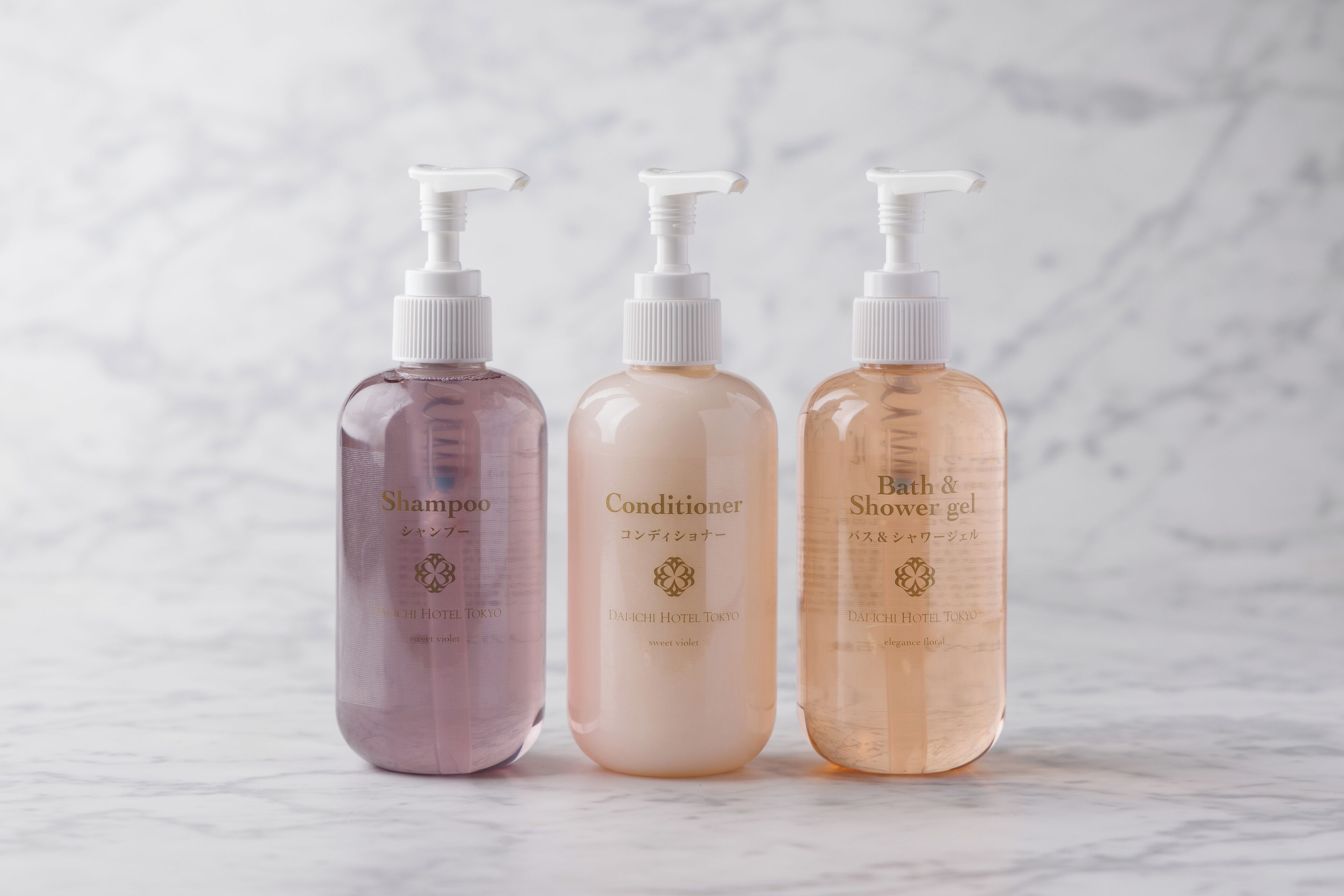 Three bottles of hotel toiletries: shampoo, conditioner, and bath & shower gel.