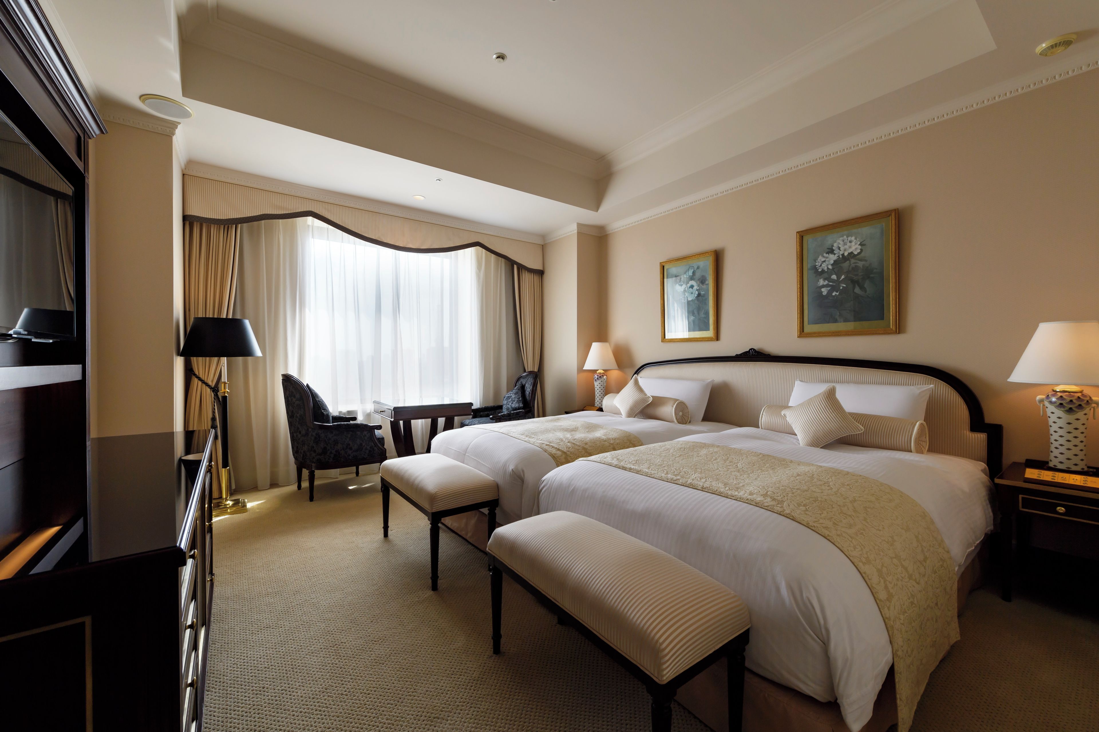 A hotel room with a large bed, two bedside tables, a desk, a chair, and a TV.