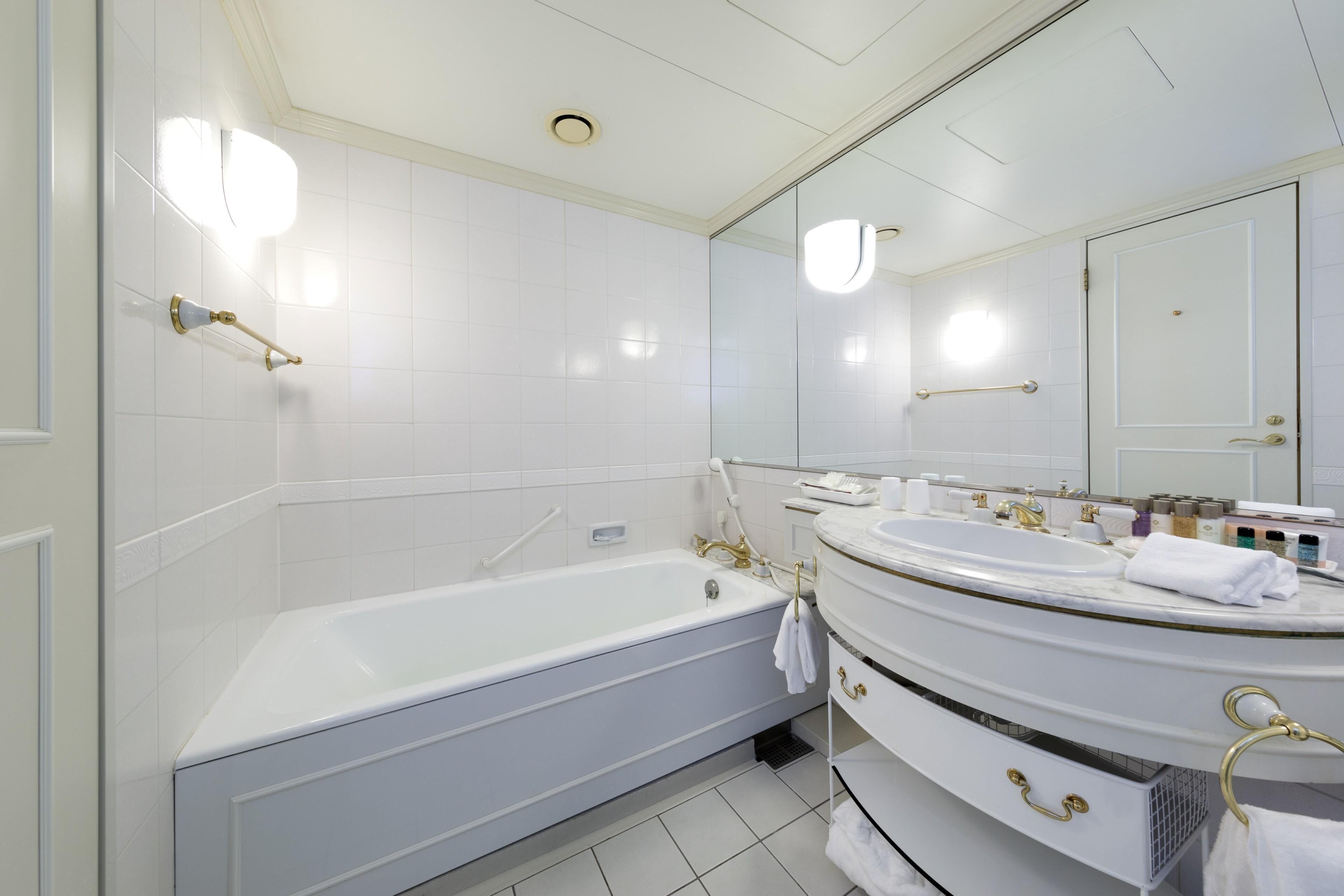 A modern bathroom with a bathtub, a large mirror, and a vanity with a sink.