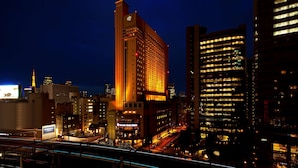 A cityscape at night with illuminated buildings, including a hotel with a visible sign.