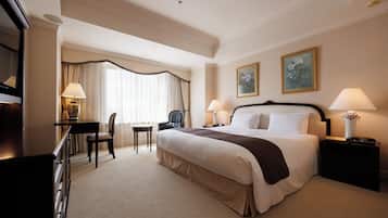 Une chambre d’hôtel avec un grand lit, un bureau avec une chaise, une petite table et deux lampes.