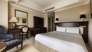 A hotel room with a large bed, a desk with a chair, a dresser, a mirror, and a lamp.