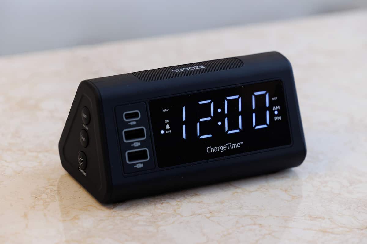 A black digital clock with a display reading 12:00 and the brand name "ChargeTime" on a marble surface.