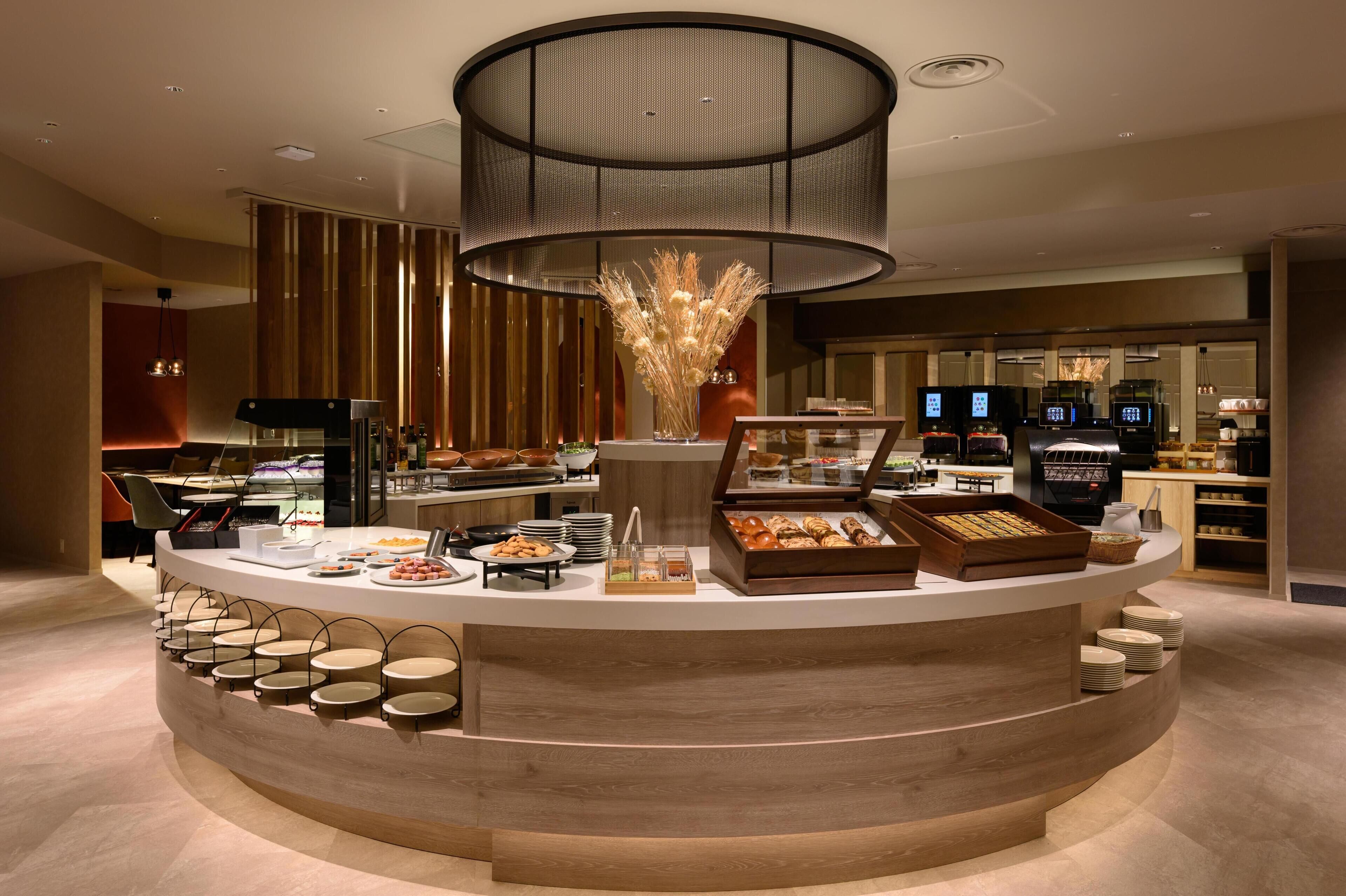 A modern breakfast bar with a variety of food options, a coffee machine, and a decorative vase.