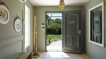 Un pasillo con un banco, una puerta que da al exterior y una lámpara colgante.