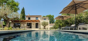 A modern pool area with a clear pool, lounge chairs, and umbrellas. - Le Vallon de Valrugues Hotel Spa & Villas (St.-Rémy-de-Provence)