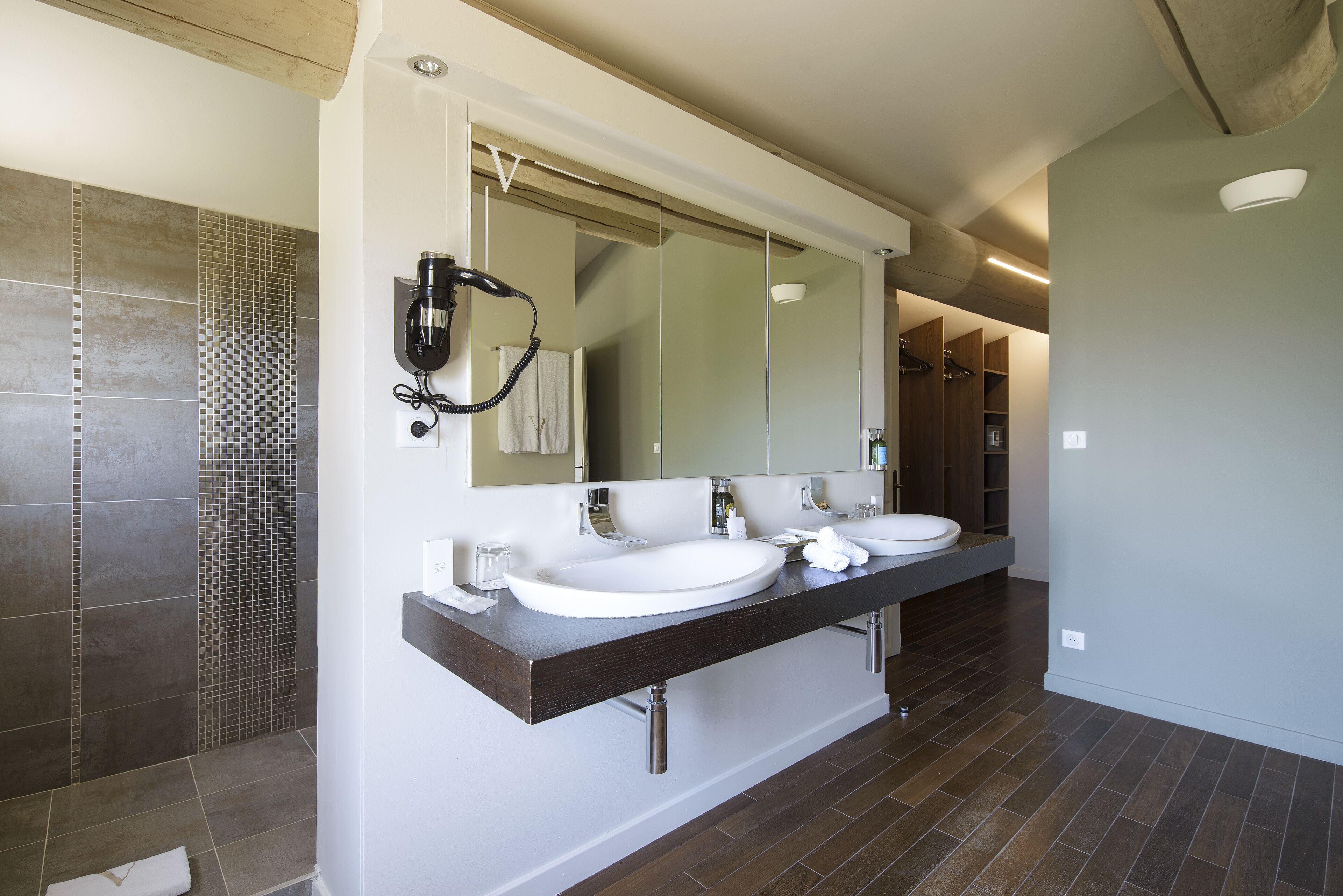 A modern bathroom with two sinks, a large mirror, and a shower area.