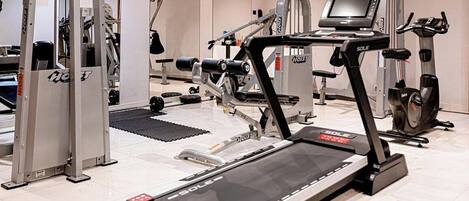 A gym with treadmills, weight machines, and a rowing machine.