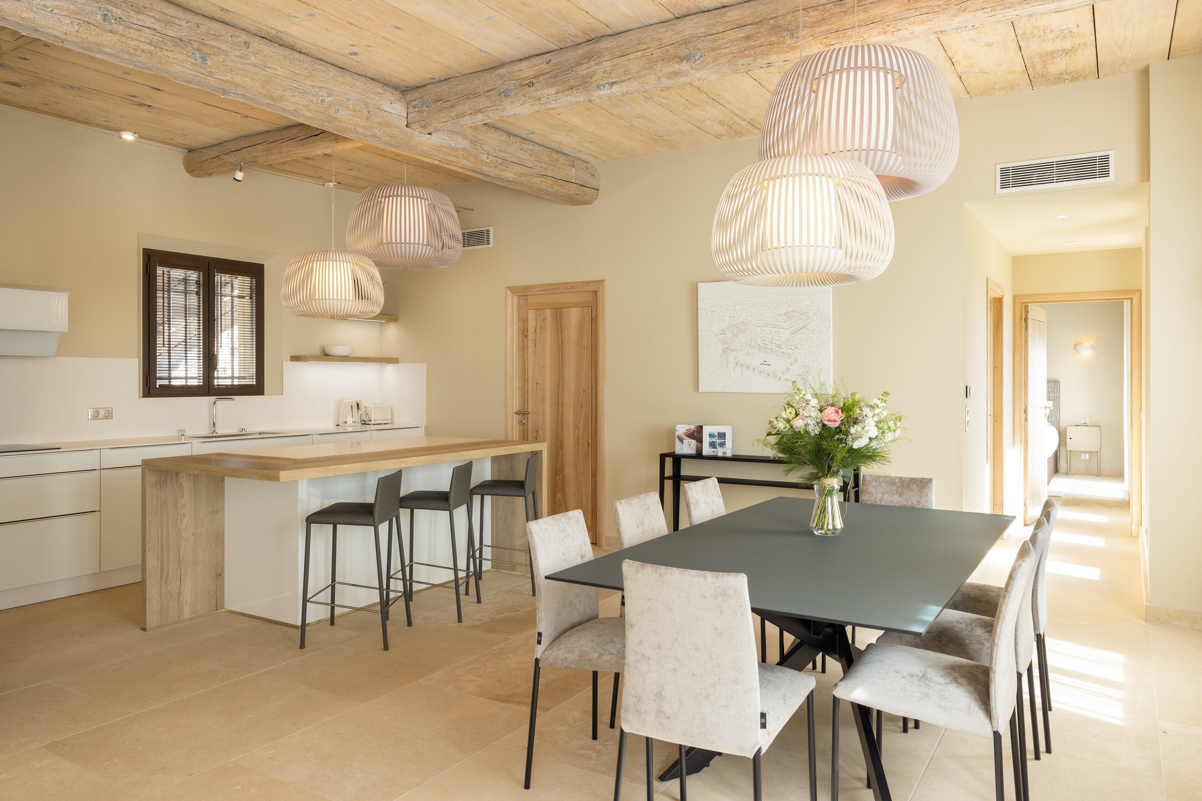 Une cuisine moderne avec un îlot central en bois, des tabourets de bar et des luminaires suspendus.