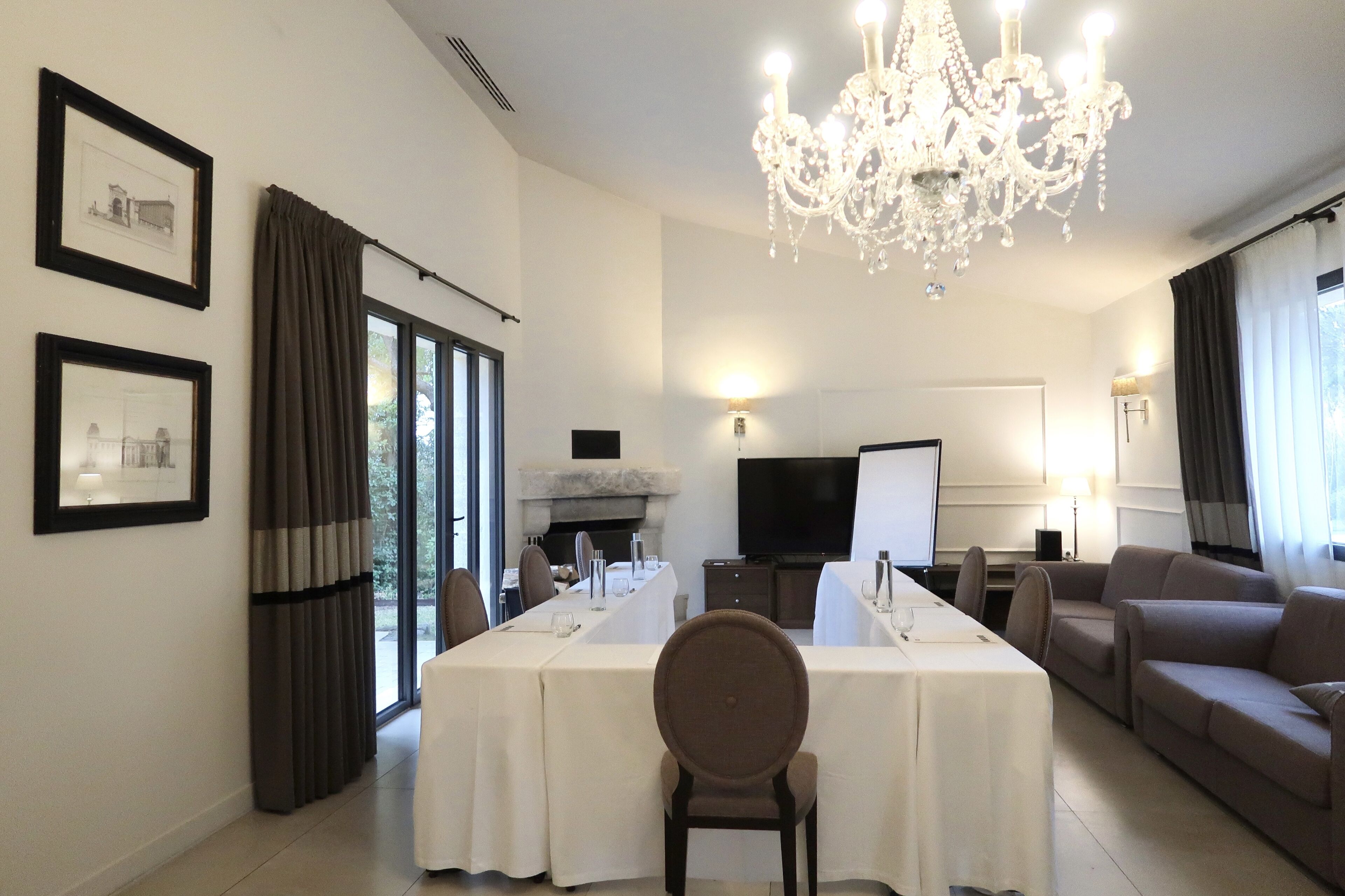 A modern hotel room with a dining area, a sofa, and a chandelier.