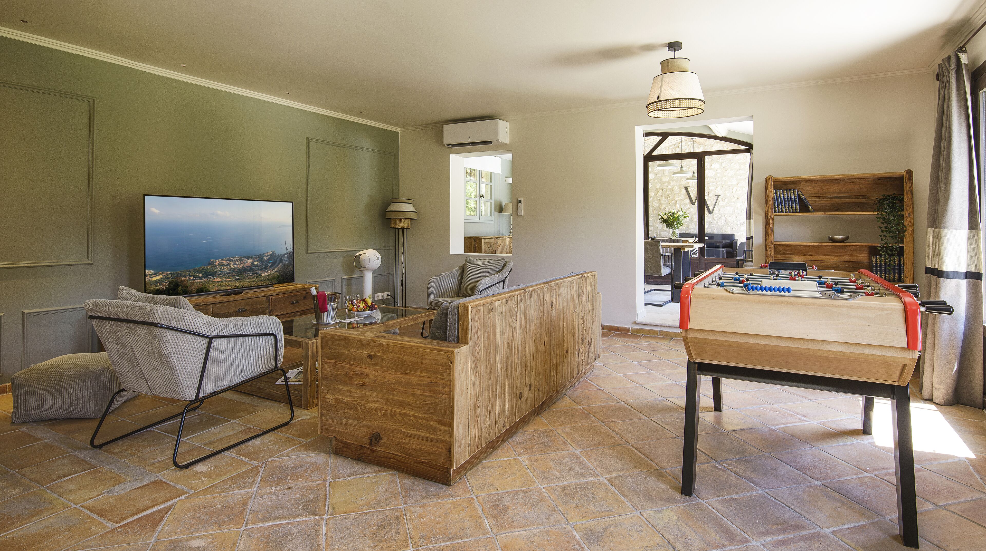 A living room with a television, seating area, and a foosball table.