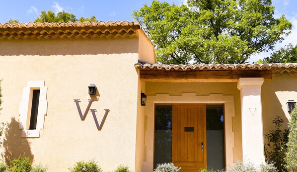 A building with a tiled roof, a wooden door, and a wall-mounted sign with the letters "VV".