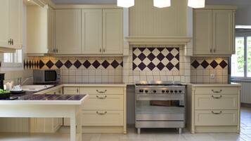A kitchen with white cabinets, a microwave, a stove, and a tiled backsplash.