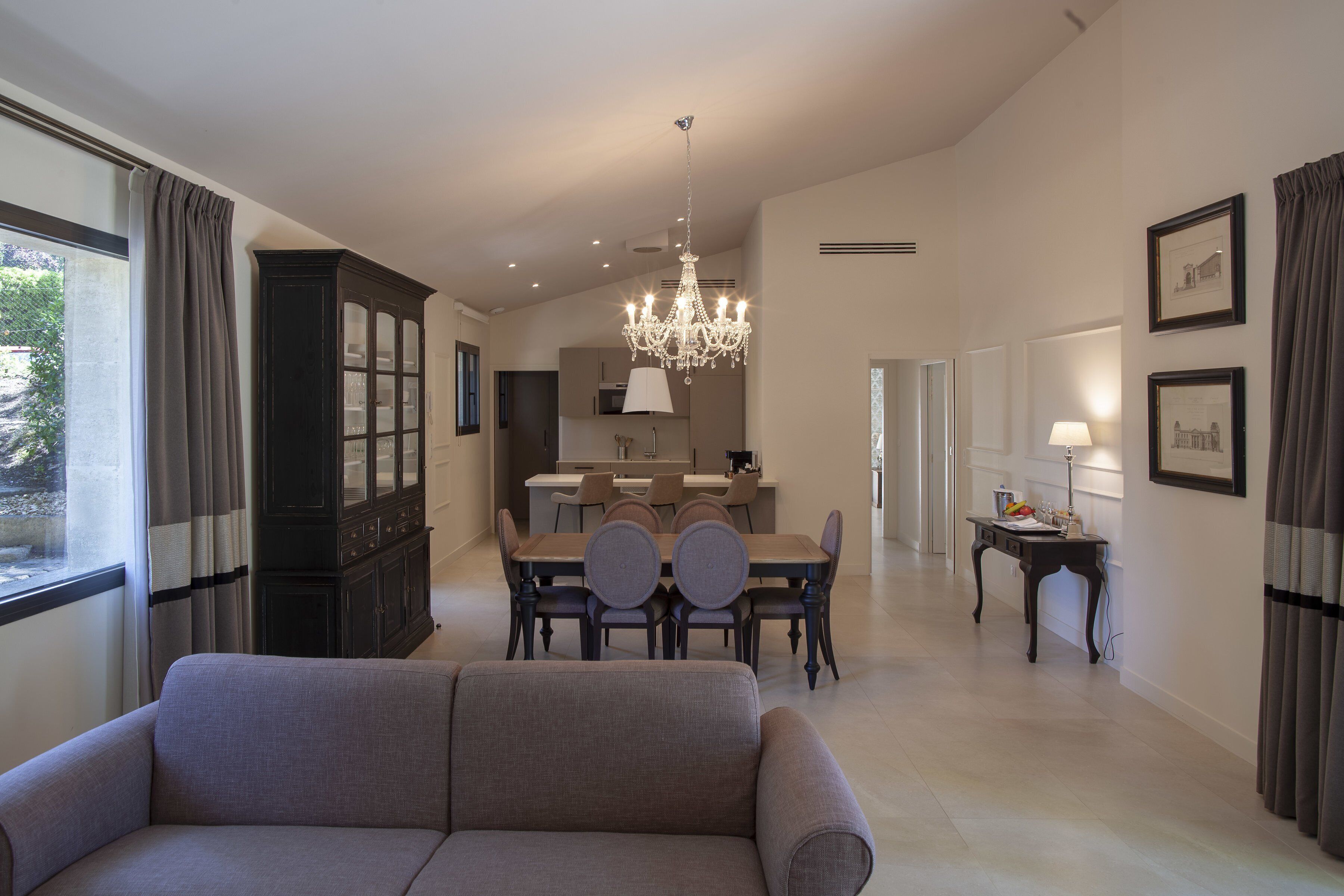 A spacious living area with a dining table, a sofa, and a chandelier.