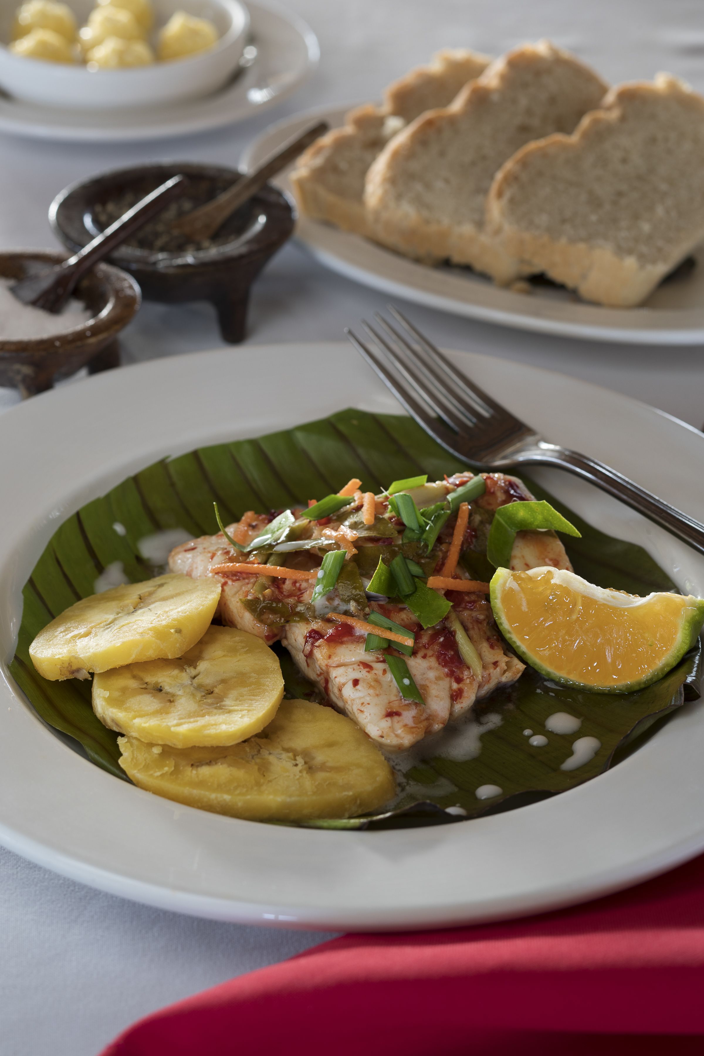 A plate of food with fish, vegetables, and a lime wedge.